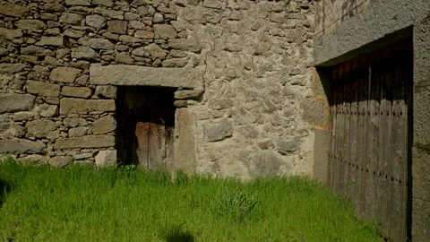 Weathered stone wall supporting two rustic wooden doors Stock Footage 335463130