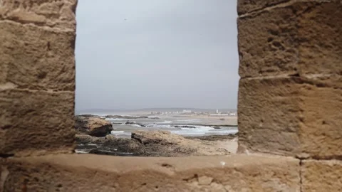 A weathered stone window frames a scenic view of the Moroccan coastline with Stock Footage 307271968