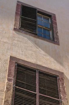 Weathered stucco wall with shuttered windows in Madeira, oblique view Foto stock