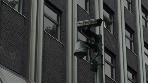 Weathered surveillance camera mounted on dark brick office building facade Stock Footage 337648173