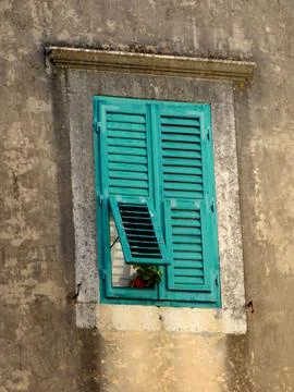 Weathered turquoise window shutters on a rustic stone wall with flower Stock Photos
