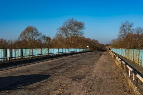 Weathered two lane bridge with rusty railings and leafless trees Stock Photos