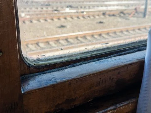 A weathered vintage train window frame overlooking railway tracks, capturing a Stock Photos