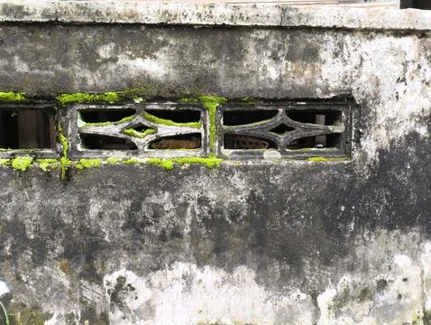 Weathered wall bears intricate window grilles Fotos Stock
