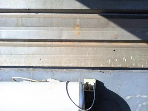 Weathered Wall with Electrical Outlet and Cable in Natural Sunlight Stock Photos