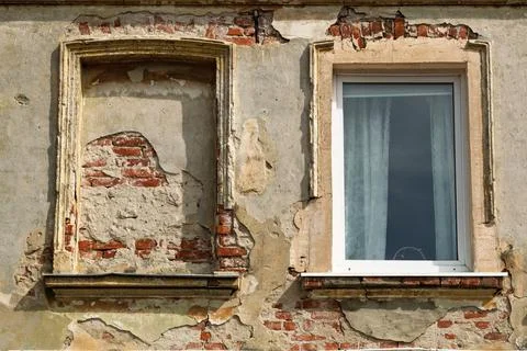 Weathered wall of an old building with peeling plaster, exposed red bricks, o Stock Photos