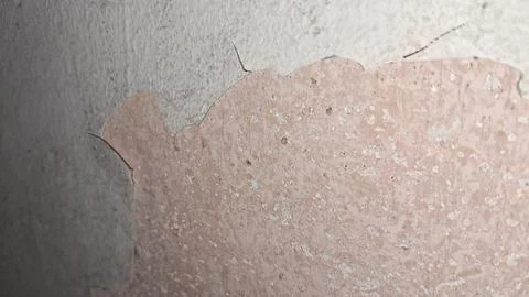 Weathered wall surface showing layers of peeling grey and pink paint Stock Photos