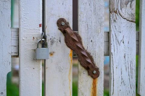 Weathered white gate with rusty latch and padlock Stock Photos