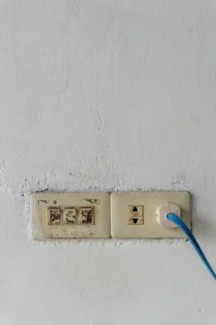 A weathered white wall featuring two old electrical outlets. 库存照片