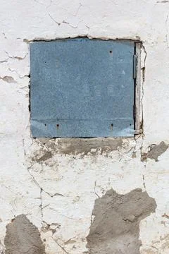 Weathered white wall with a square blue panel Stock Photos