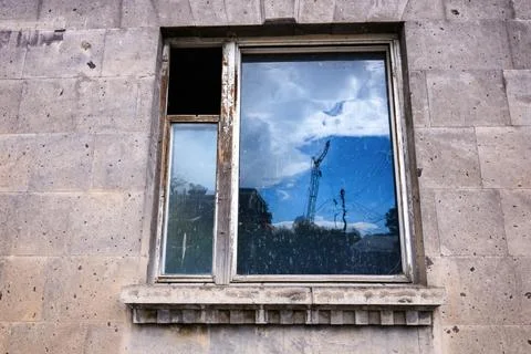 Weathered window with broken pane reflects crane and trees Stock Photos