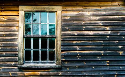 Weathered window in the wall of a charred colonial building Foto stock
