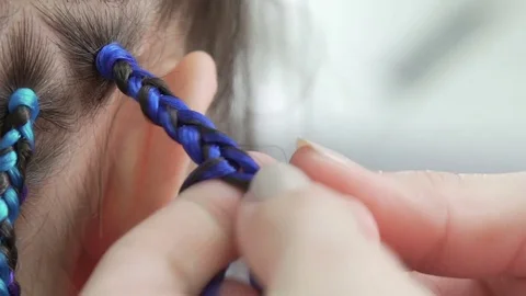 Weaving braids with blue artificial strands: close-up Video stock 76577187