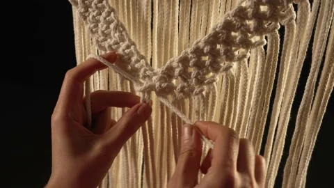 Weaving macrame pattern from natural white cotton threads. Women's hands knit Stock Footage 172242364