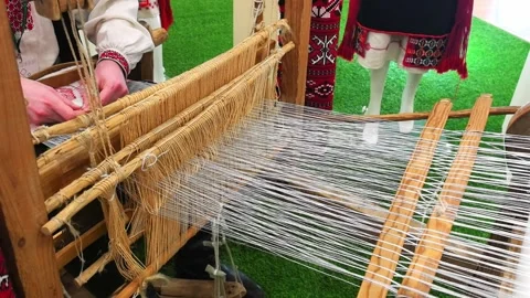 Weaving thread using a loom at a cultural exhibition in a local community center Stock Footage 326375333