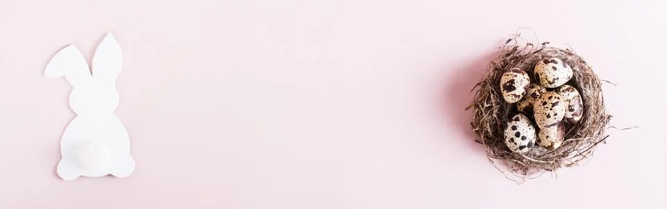 Web banner happy easter quail eggs in natural nest and white rabbit on pink.. Stock Photos