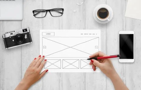 Web designer draw layout of website on paper. Top view of work desk with comp Stock Photos