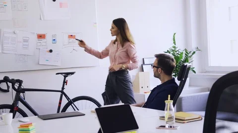 Web designers discussing mobile app layout on whiteboard Stock Footage 102848479