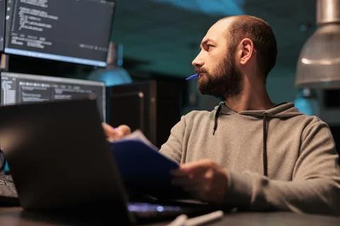 Web developer analyzing source code with papers Stockfoto's