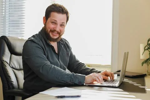 Web developer sitting at office desk working on laptop computer. Stock Photos