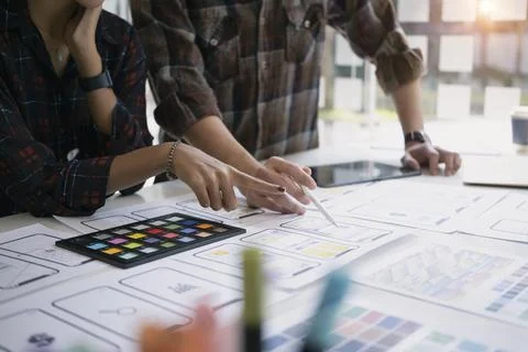 Web developers discussing and planning interface of mobile website with layouts Stock Photos