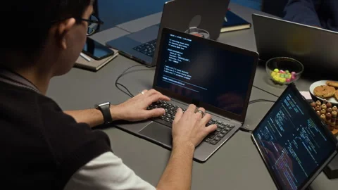 Web Engineer Working on Laptop with Code Running on Screen in Dimly Lit Office Stock Footage 329615330