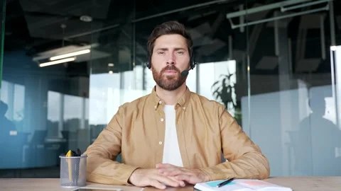Webcam view. Confident businessman in wireless headphones talking on a video  Stock Footage 295038802