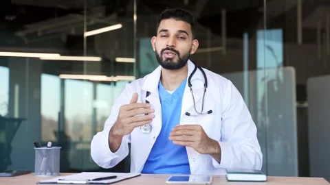 Webcam view. Confident doctor talking on video call sitting in hospital office  Stock Footage 320619230