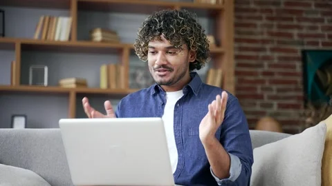 Webcam view. Young man talking on video call looking at camera sitting on sofa  Video stock 334226454