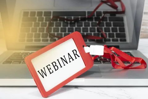 Webinar text written on red name tag placed on a laptop. Stock Photos