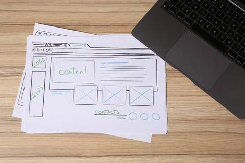 Website development. Sketches of wireframes and laptop on wooden table, fla.. Foto stock