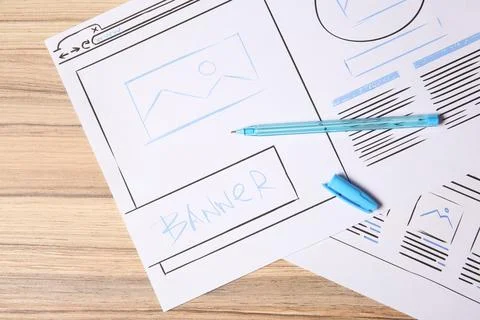 Website development. Sketches of wireframes and pen on wooden table, flat lay 스톡 사진