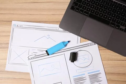 Website development. Sketches of wireframes, highlighter and laptop on wood.. Foto stock