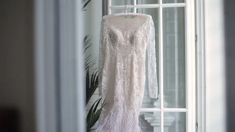 Wedding accessories, festive day. The white dress of the bride hangs on an open  Stock Footage 113064553