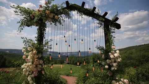 Wedding arch on boho style with white flowers in park with light bulbs. Stock Footage 157886787