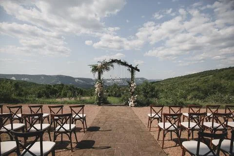 Wedding arch on boho style with white flowers in park with light bulbs. Stock Photos