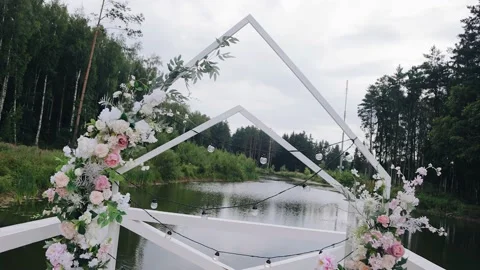 The wedding arch decorated with flowers and light bulbs stands on the pier Stock Footage 172462005