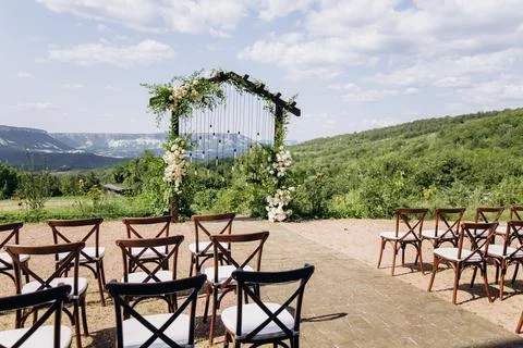 Wedding arch on rustuc style with white flowers in park with light bulbs. Stock Photos