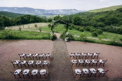Wedding arch on rustuc style with white flowers in park with light bulbs. Stock Photos