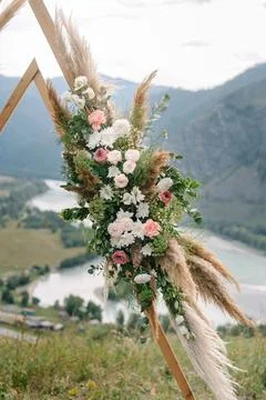 Wedding arch in the shape of a triangle with flowers Stock Photos