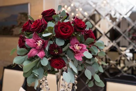 Wedding arrangement with red roses, orchids and eucalyptus on the banquet table Stock Photos
