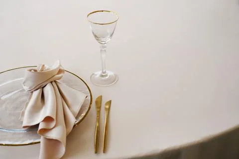 Wedding banquet table setting with white tablecloth, gold-rimmed plate, folded Stock Photos