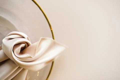 Wedding banquet table setting with white satin napkin tied in a knot on a gold Stock Photos