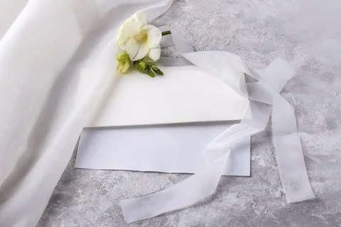 Wedding blank and an envelope with a delicate freesia flower on a light table Stock Photos