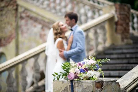 Wedding bouquet in focus and couple in the background. Stock Photos
