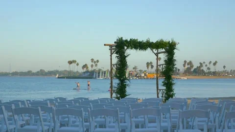 A wedding ceremony setup by the water with an arch and chairs in San Diego,.. Stock Footage 284077691