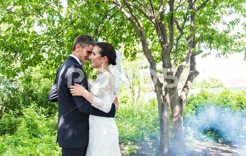 Wedding Couple Against The Backdrop Of A Misty Garden