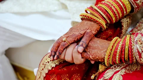 Wedding couple hold by the hands of each other, dressed in traditional red Видео 310430258