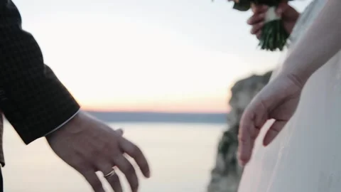 Wedding couple holds hands at sunset. The sun's rays shine through their fingers Vídeo Stock 131339816