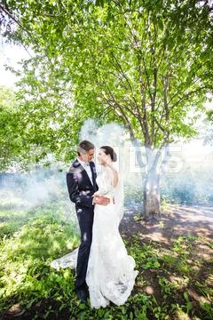 Wedding Couple Kissing Against The Backdrop Of A Misty Garden